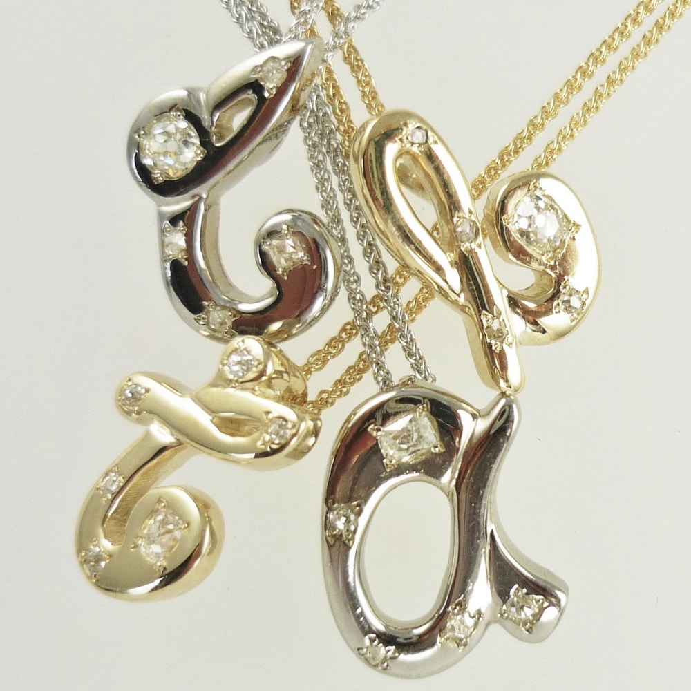 Diamond set initial pendants in white and yellow gold